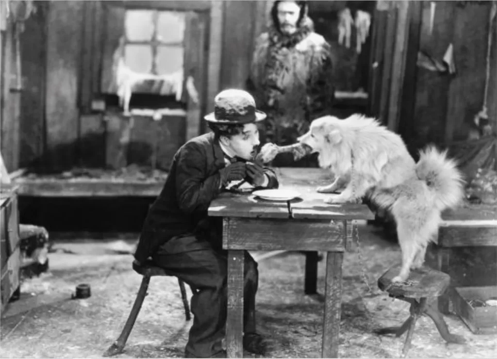 Charles Chaplin kämpft mit dem Spitz um einen Knochen
(Film "Goldrausch" von 1925)